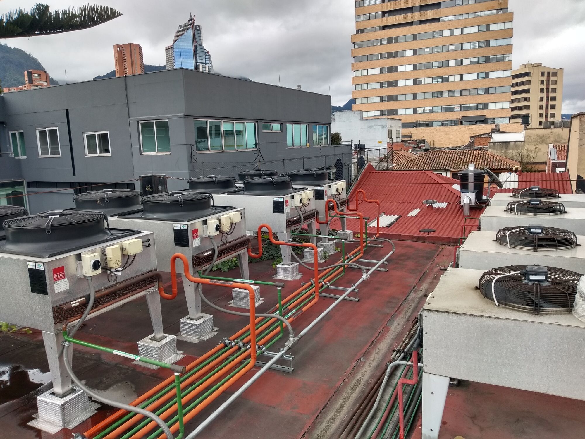 Fila de condensadoras con tuberías de refrigerante identificadas por colores sobre una cubierta